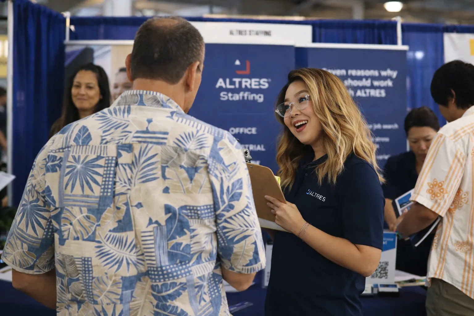 A recruiter at the ALTRES Staffing booth smiles while talking with a job seeker at the Hawaiʻi Career Expo